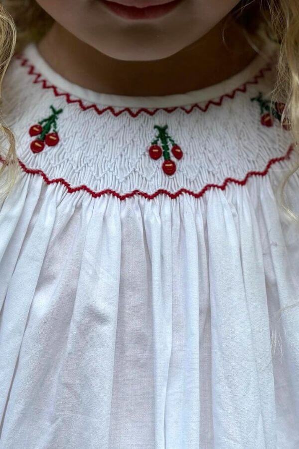 Smocked Cherry Bishop Dress (6) featuring hand-smocked cherries on a white fabric neckline.