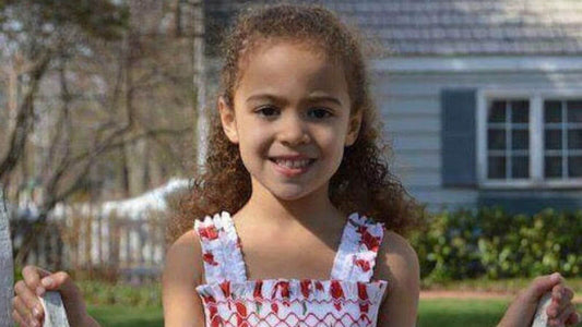 Smiling young girl in a smocked sundress enjoying a sunny summer day