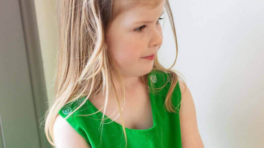 Girl in Liberty of London green dress by Emily Lacey, showcasing stylish and comfortable kidswear.