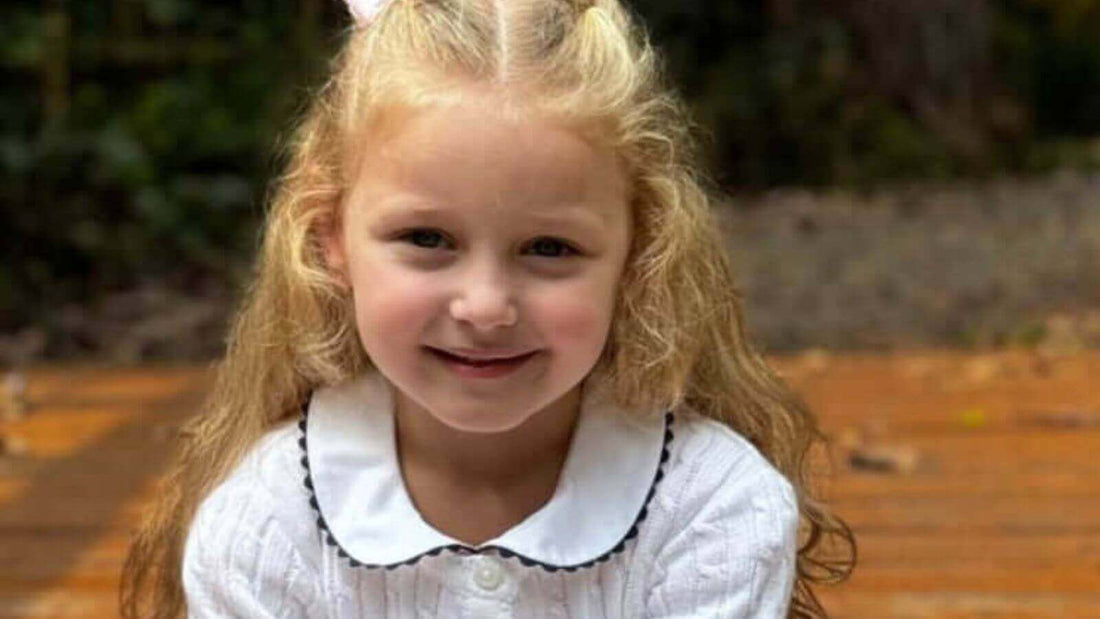 Smiling child in Emily Lacey White Cotton Cable Knit Cardigan enjoying a day outdoors.