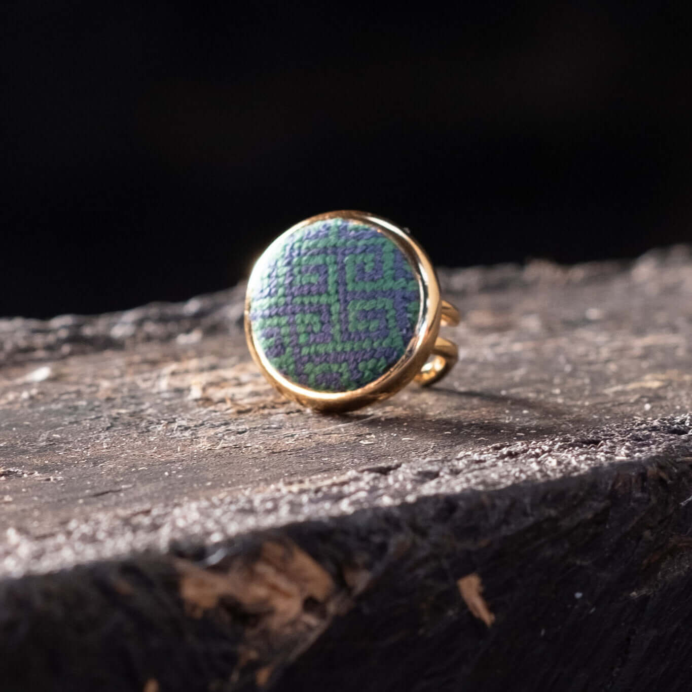 Navy & Kelly Greek Key Needlepoint Ring on a rustic surface, showcasing its unique design and adjustable fit.