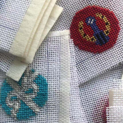 Close-up of colorful needlepoint designs on mesh fabric, showcasing intricate patterns and textures for crafting.