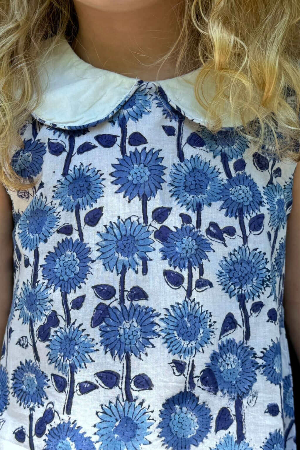 Close-up of a girl wearing a Blue Sunflower Floral Dress with a white collar, showcasing charming blue and white floral print.