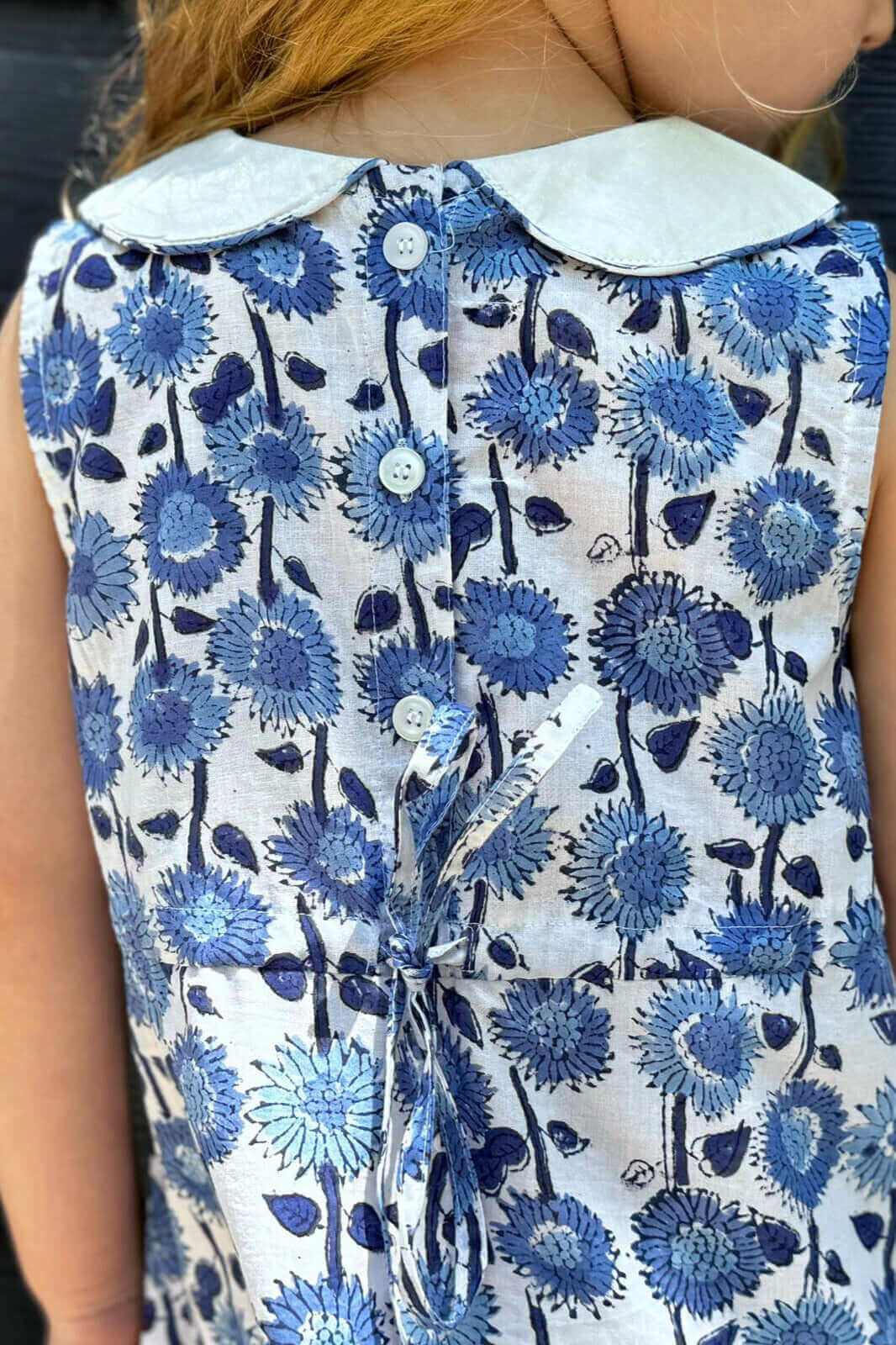 Closeup of a Blue Sunflower Dress with charming blue and white floral print and button details, perfect for a stylish school day.