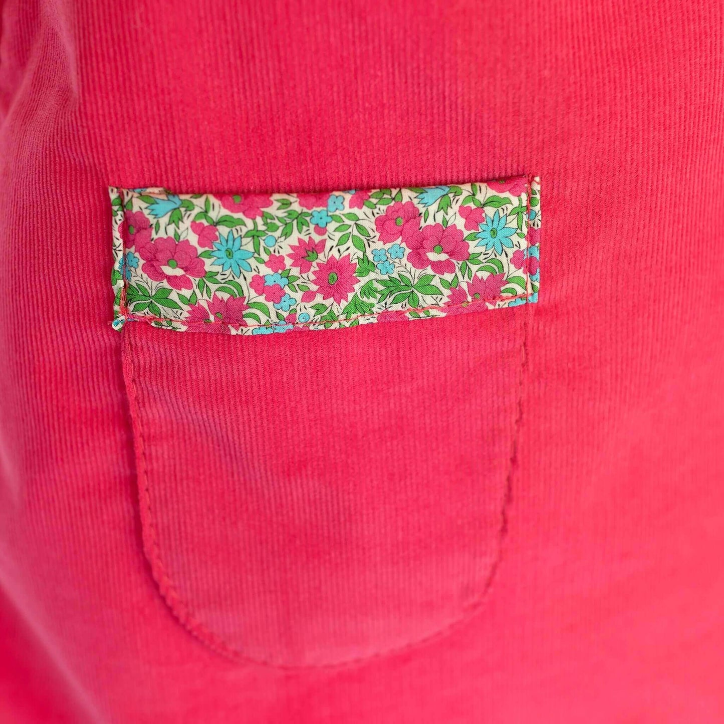 Liberty of London pink dress pocket with floral trim design, showcasing bright elegance and style for girls' fashion.