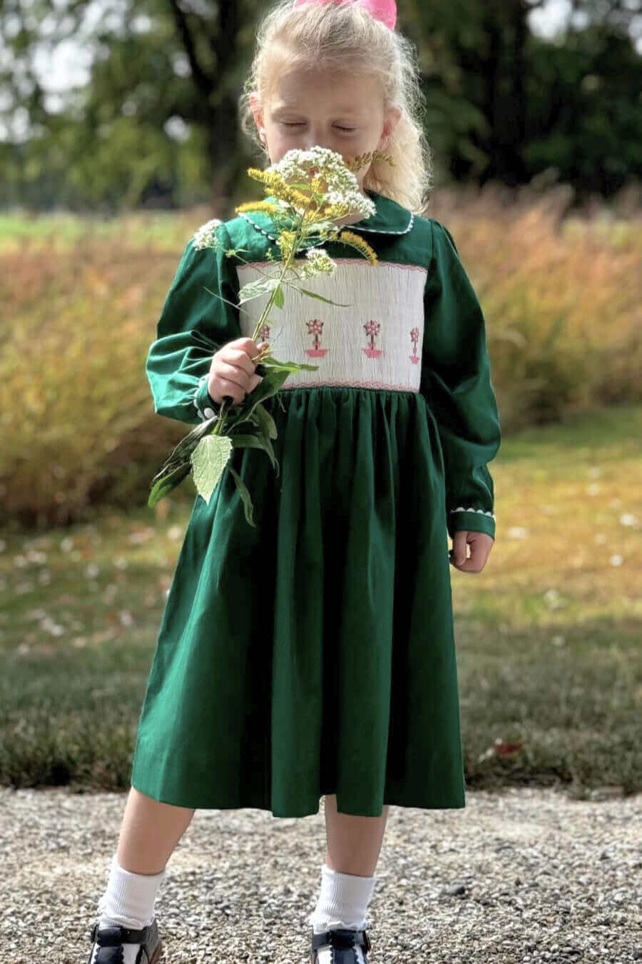 Little girl in Smocked Green Topiary Dress holding flowers outdoors