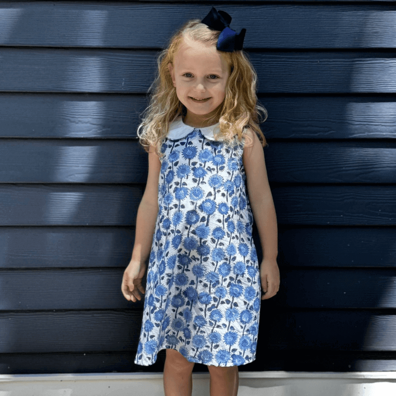 Smiling girl wearing a Blue Sunflower Dress with a fresh Provence floral print, Peter Pan collar, and belt, perfect for back to school.