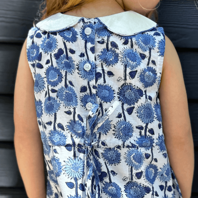 Back view of a sleeveless A-line dress with blue sunflower floral print, white Peter Pan collar, buttons, and a belt, perfect for back-to-school.