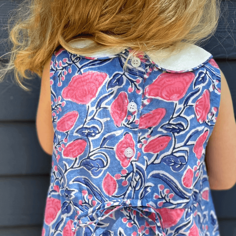 Girl wearing a Sky and Pink Floral Dress with Peter Pan collar and back buttons, watercolor print perfect for school.