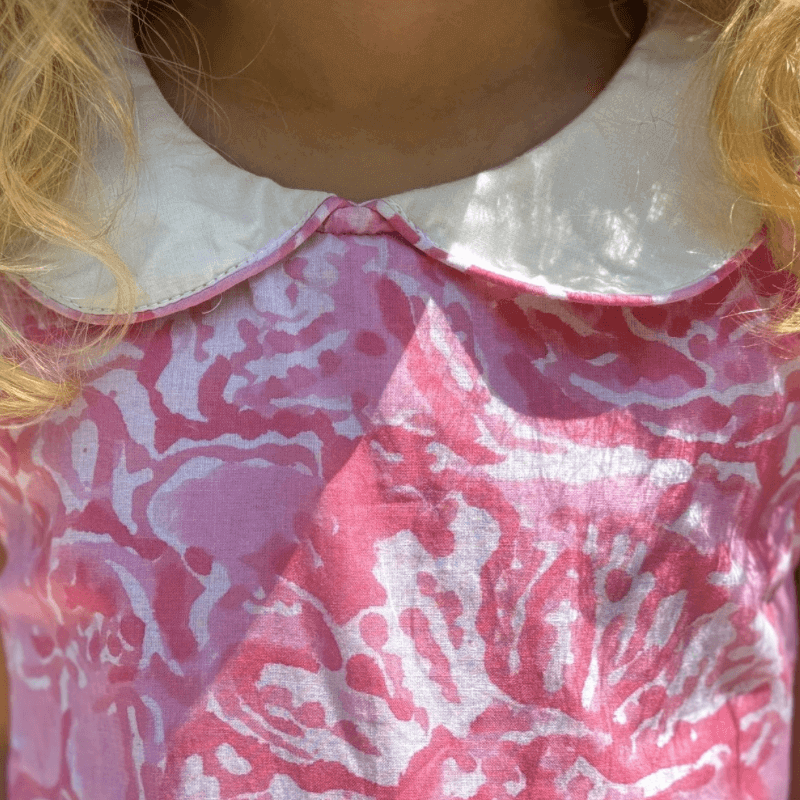 Close-up of a pink watercolor A-line dress with a Peter Pan collar, perfect for back-to-school fashion.