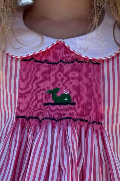 Pink and white striped Smocked Whale Dress with whale embroidery and Peter Pan collar, showcasing artisanal beauty and craftsmanship.