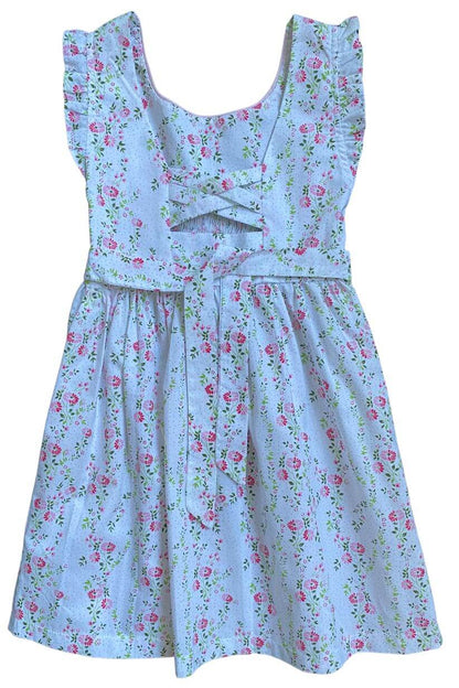 Hand-smocked pink ruffle floral dress featuring delicate embroidery and flutter sleeves on a blue background.