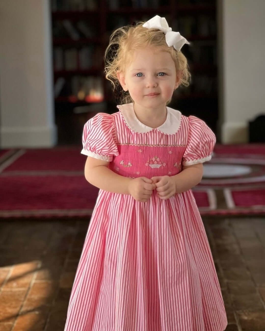 Adorable child in pink striped dress with hand-smocked lovebirds and flower basket design.