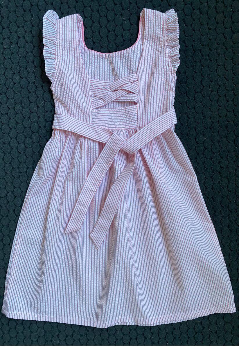 Darling pink and white seersucker smocked dress with ruffle sleeves and belt, perfect for little fashionistas!