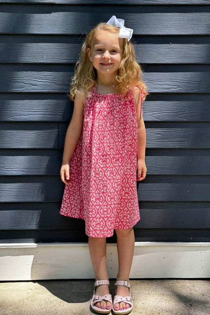 Little girl in pink floral watercolor print sun dress standing and smiling