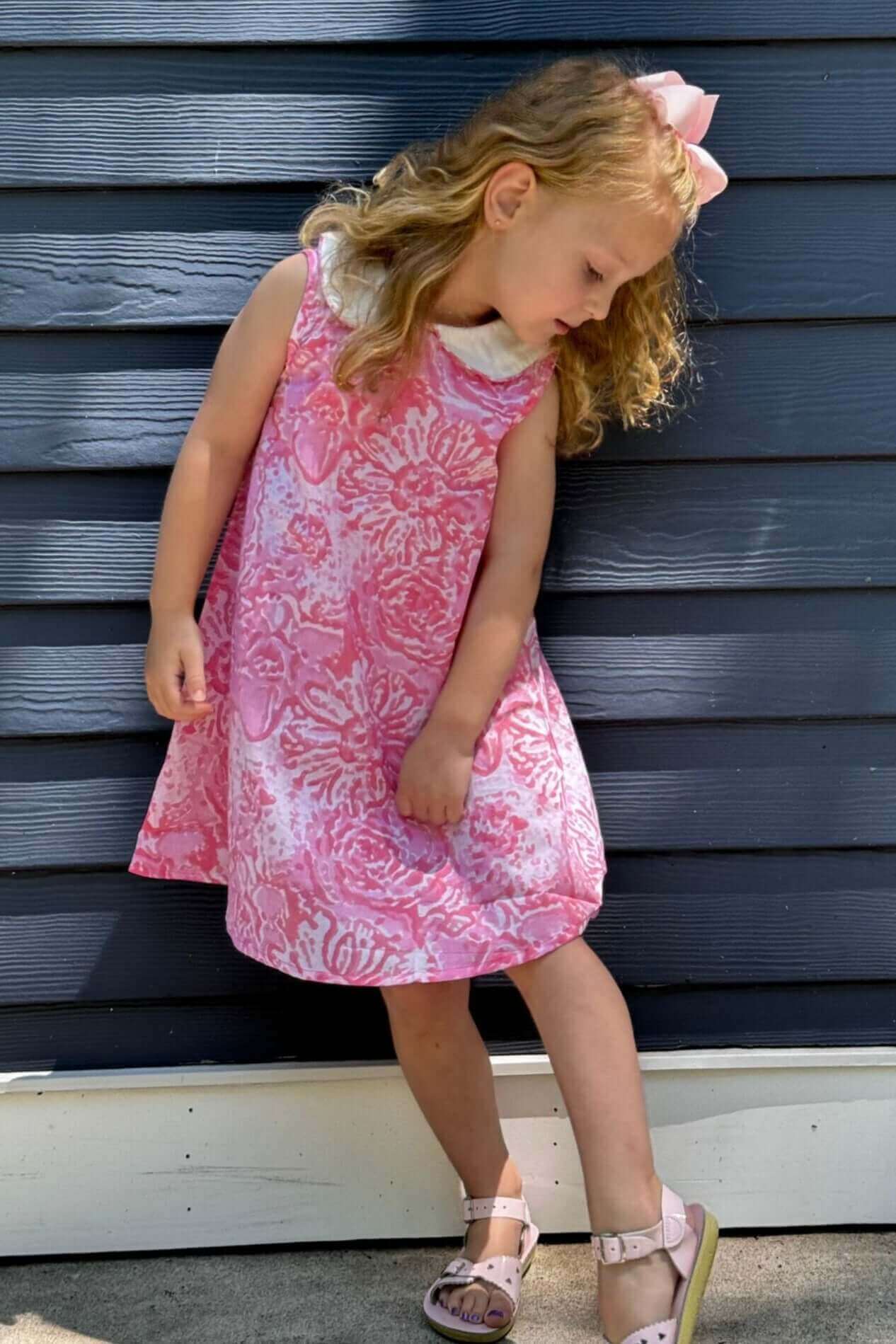 Young student shines in a pink watercolor print dress with a charming Aline cut, perfect for adding fun and flair to school days.