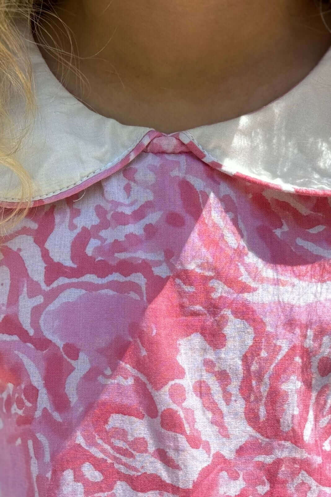 Close-up of a girl wearing a Pink Watercolor Print Dress with a white collar, showcasing the vibrant artistic pattern and comfortable fabric.