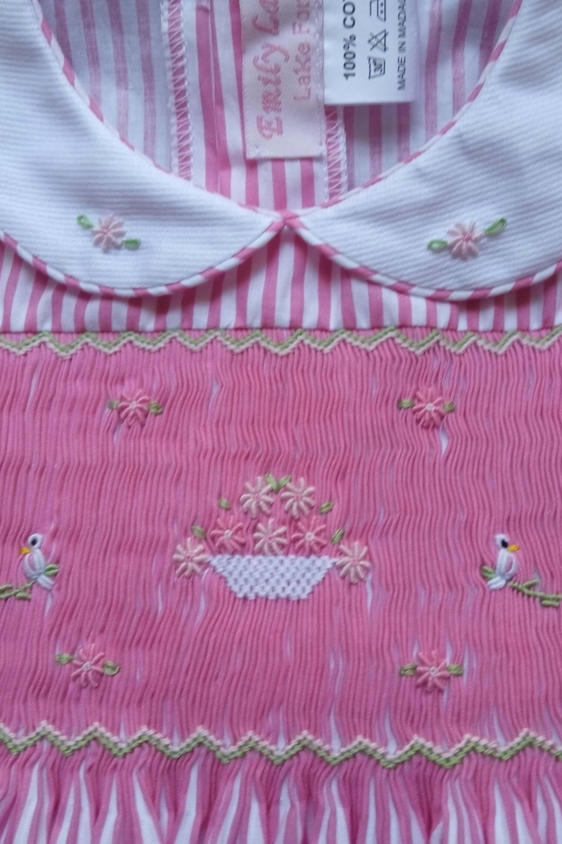 Hand-smocked pink dress featuring lovebirds and a flower basket design with detailed craftsmanship.