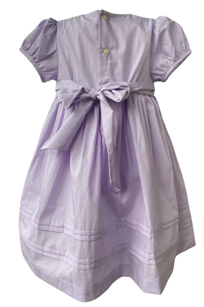 Elegant violet hand-smocked dress with floral embroidery and bow, perfect for special occasions.