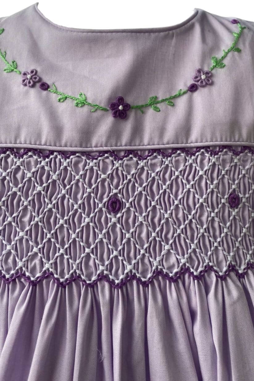 Close-up of the SAMPLE Smocked Violet Dress featuring delicate floral embroidery and hand-smocked design.