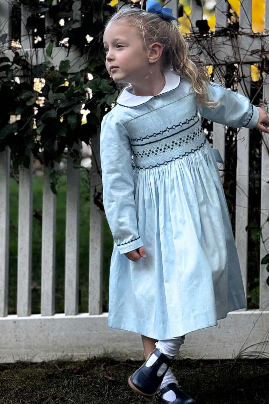 Little girl twirling in a Smocked Sky Blue Geo Dress, perfect for school photos, birthday celebrations, and holidays.