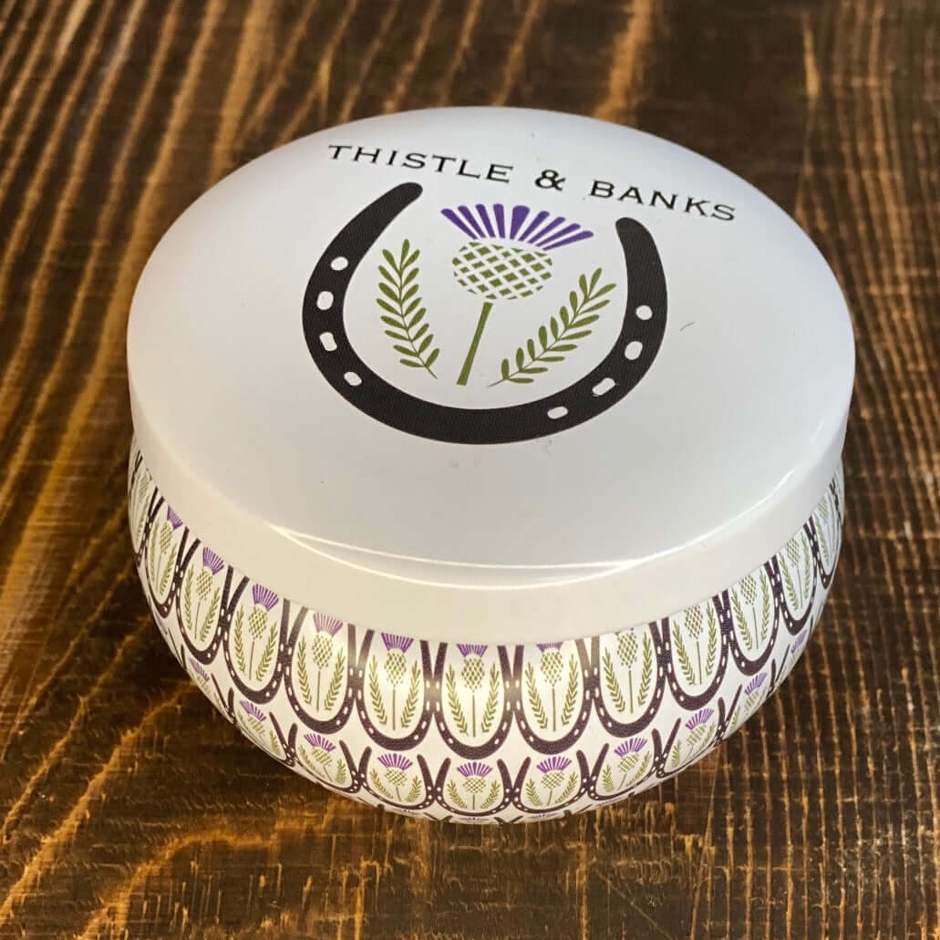 Thistle & Banks decorative round box featuring a horse shoe and floral design on a wooden surface. Perfect for equestrian gifts!