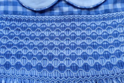 Close-up of hand-smocked detailing on Smocked Azure Gingham Dress, featuring vibrant blue gingham patterns.