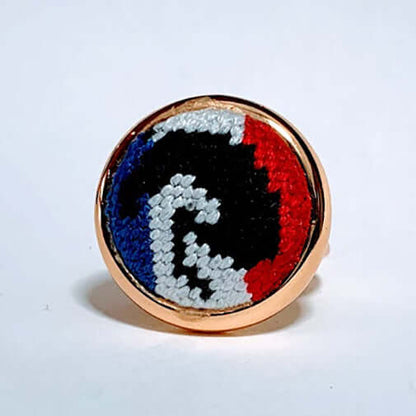 Tricolor Jumper Needlepoint Ring with red, black, and blue equestrian design on adjustable setting. Perfect horse lover gift.